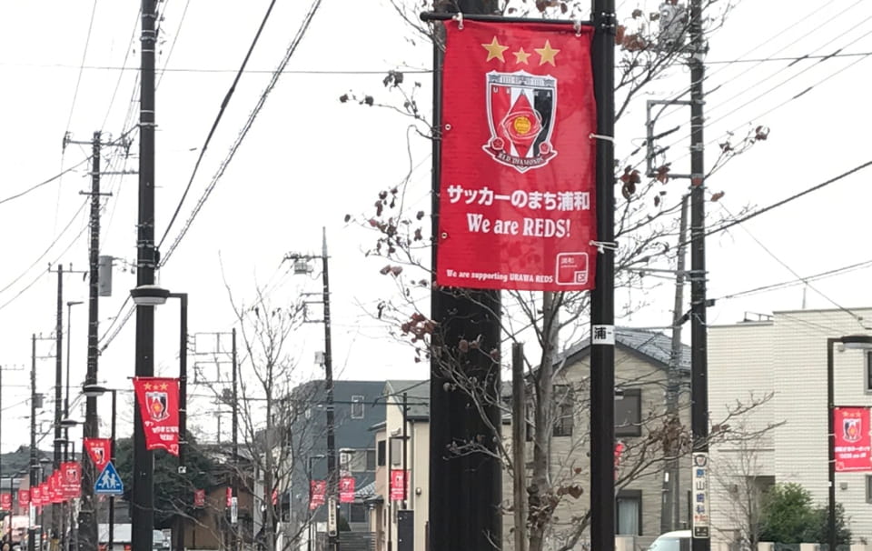 画像:浦和レッズロゴと「サッカーのまち浦和 We are REDS!」が書かれたバナーフラッグ